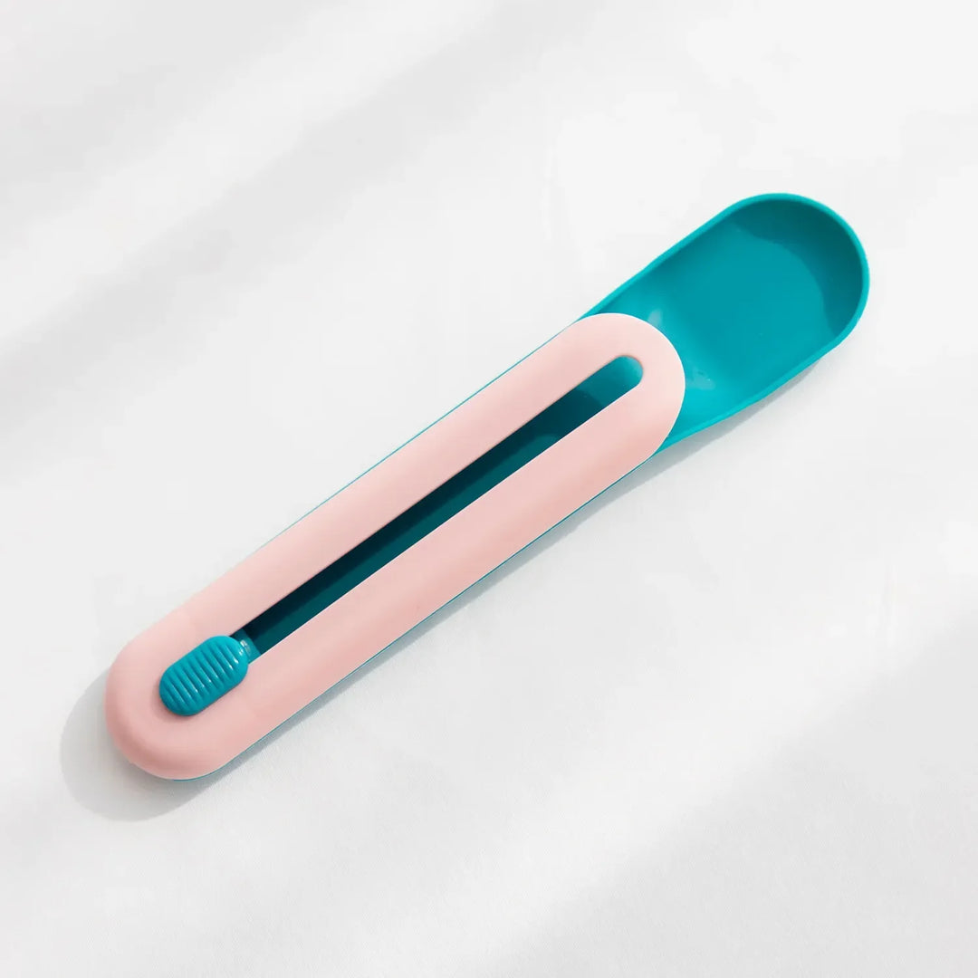 Close-up of pet food dispenser spoon with orange slider mechanism, ideal for squeezing wet food tubes.