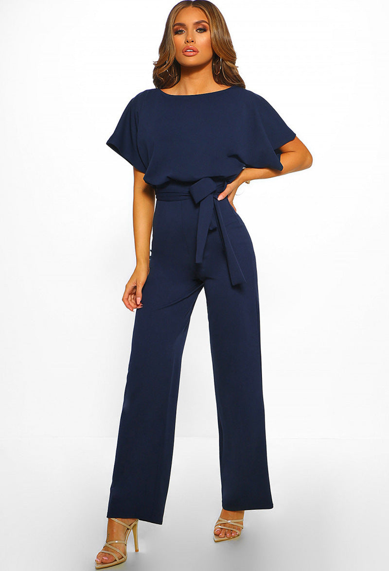 Woman modeling a chic wide-leg jumpsuit with a tied waist, ideal for elegant occasions or casual wear.