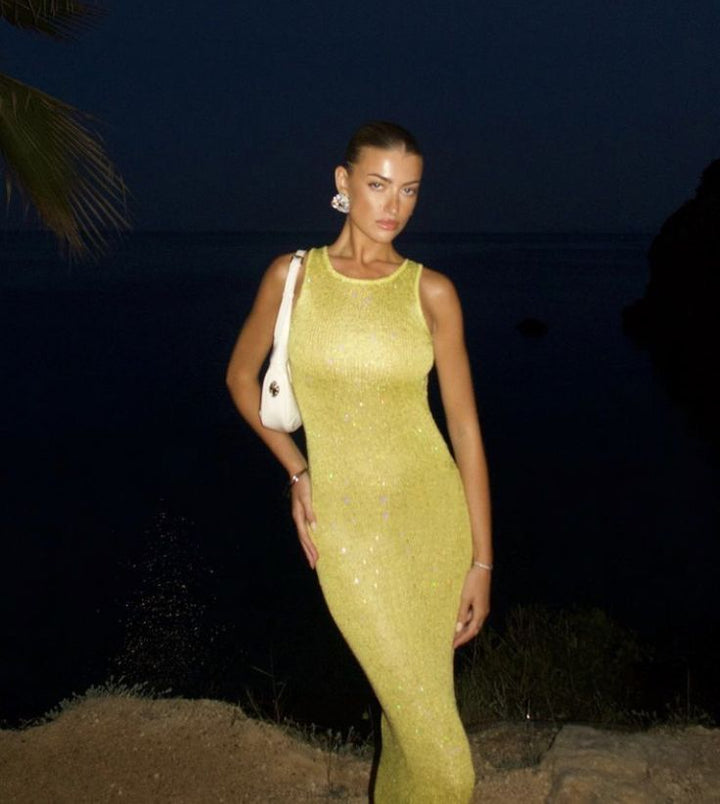 Woman models a glamorous yellow shimmering sleeveless maxi dress, ideal women's party wear & evening gown.