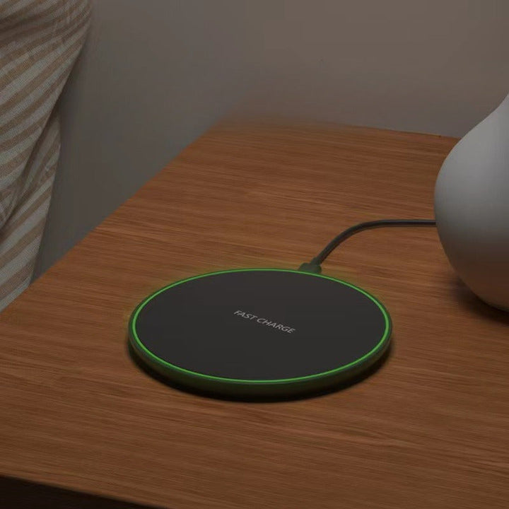 Black Fast Wireless Charger on a modern desk setup. Essential smartphone accessory for quick iPhone & Android power.