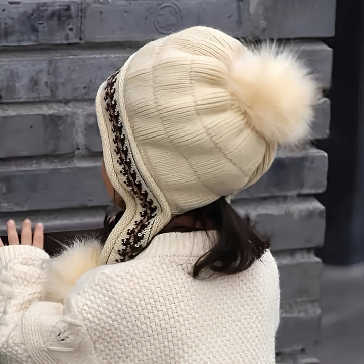 Kids' ear flap winter hat featuring braided ties and two pom-poms, providing secure warmth for little ears.