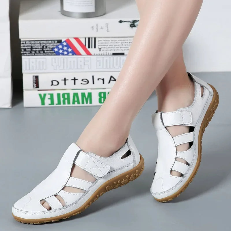 Side view: Women's brown leather flat sandals with adjustable velcro straps & ergonomic comfort sole.