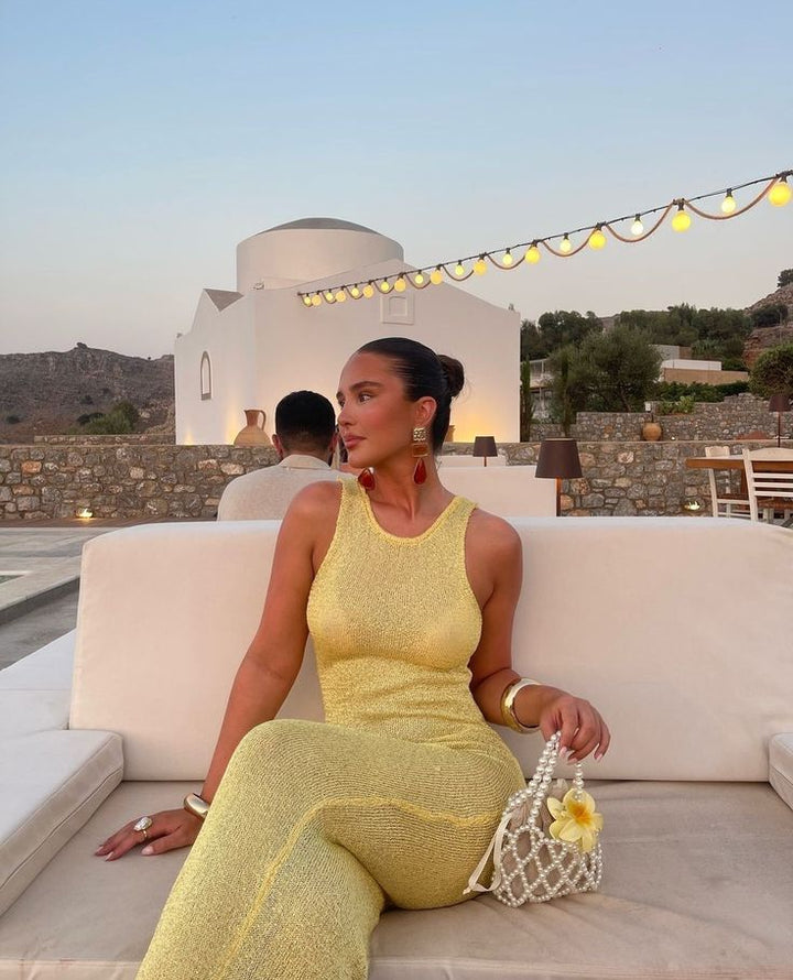 Close-up of the shimmering fabric on a yellow women's maxi dress, highlighting its glamorous texture.