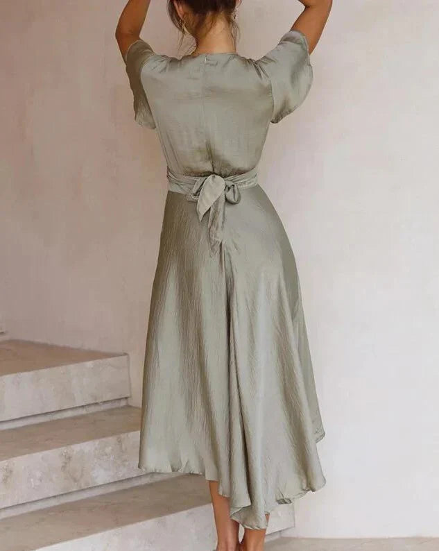 Stylish green V-neck midi dress for women, featuring a flattering tie-waist and flowy asymmetrical hem. Ideal for evening wear.