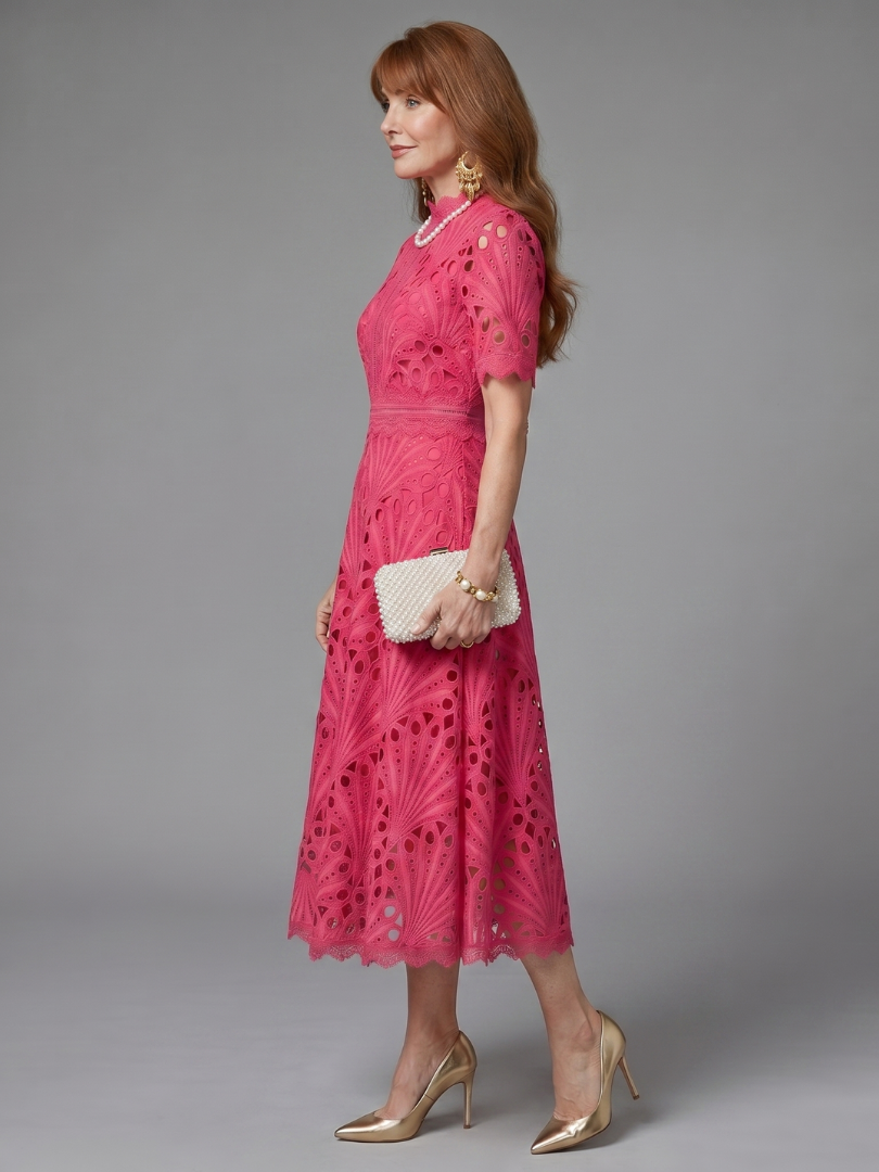 Close-up of a pink eyelet lace midi dress, showing delicate floral patterns & a feminine fitted waist.