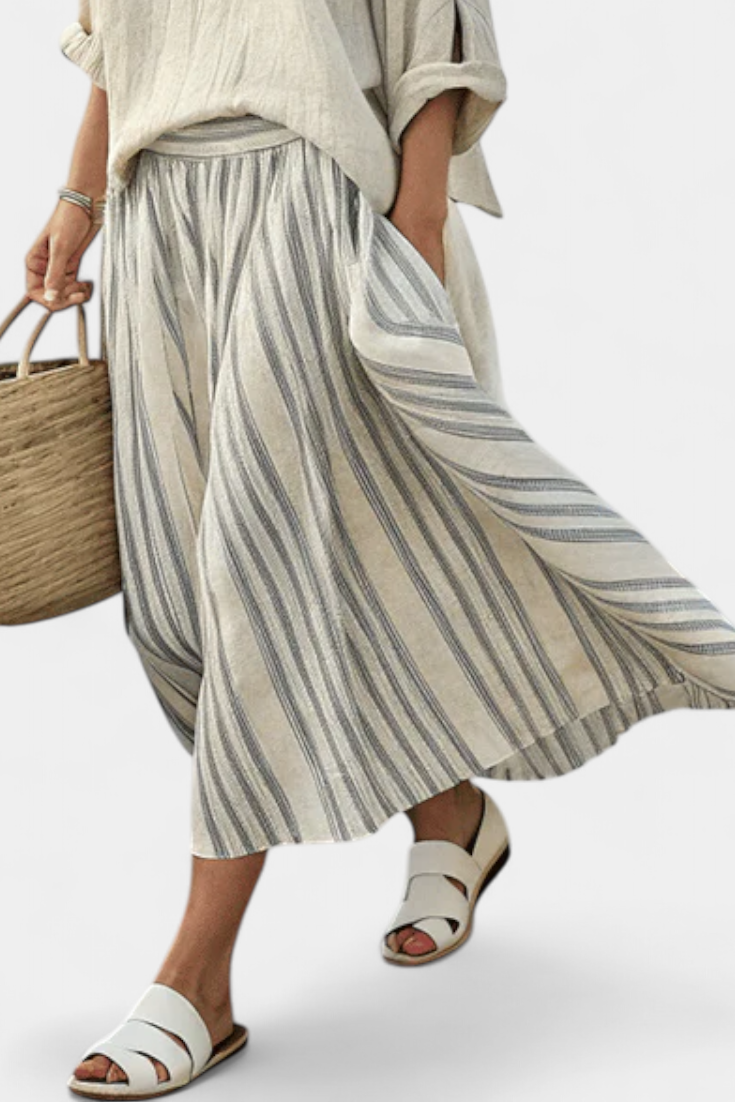 Comfortable women's loose blouse and striped midi skirt set, ideal for a chic summer or vacation look.