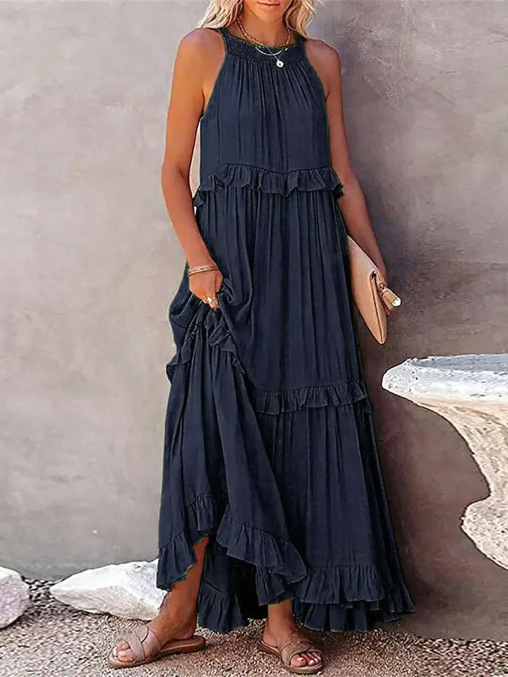 Blue flowy halterneck maxi dress with ruffles & pockets, ideal for holiday elegance.