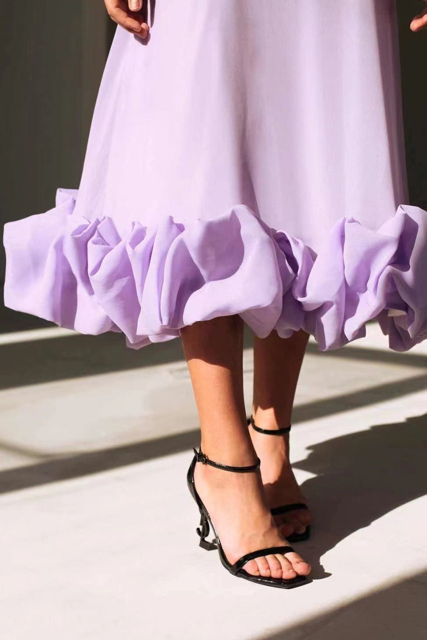Women's graceful flowing midi dress worn at an elegant outdoor occasion, perfect chic formal wedding guest attire.