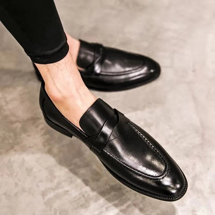 Man wearing polished black leather slip-on penny loafers, showcasing classic style & comfort for work or events.
