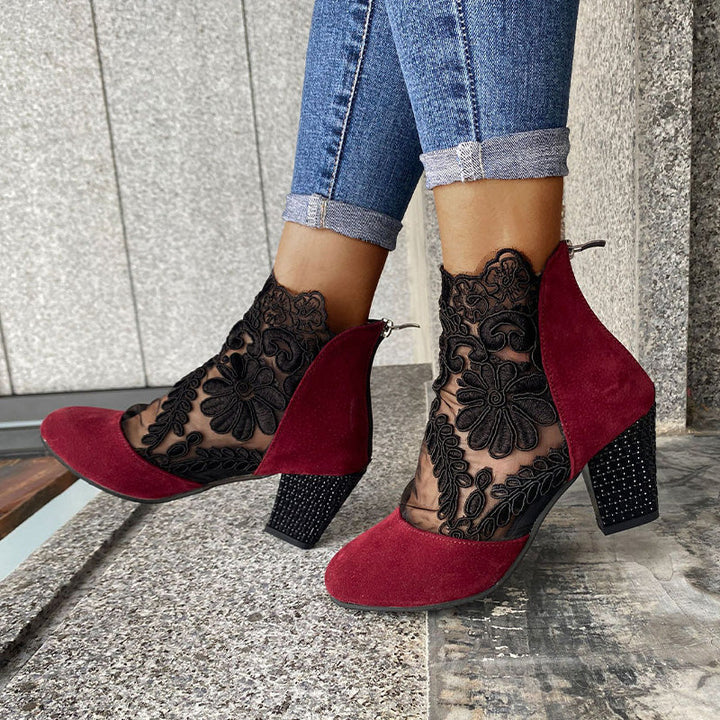 Close-up: Delicate lace embroidery on elegant women's black ankle boots with a comfortable block heel. Detail shot.