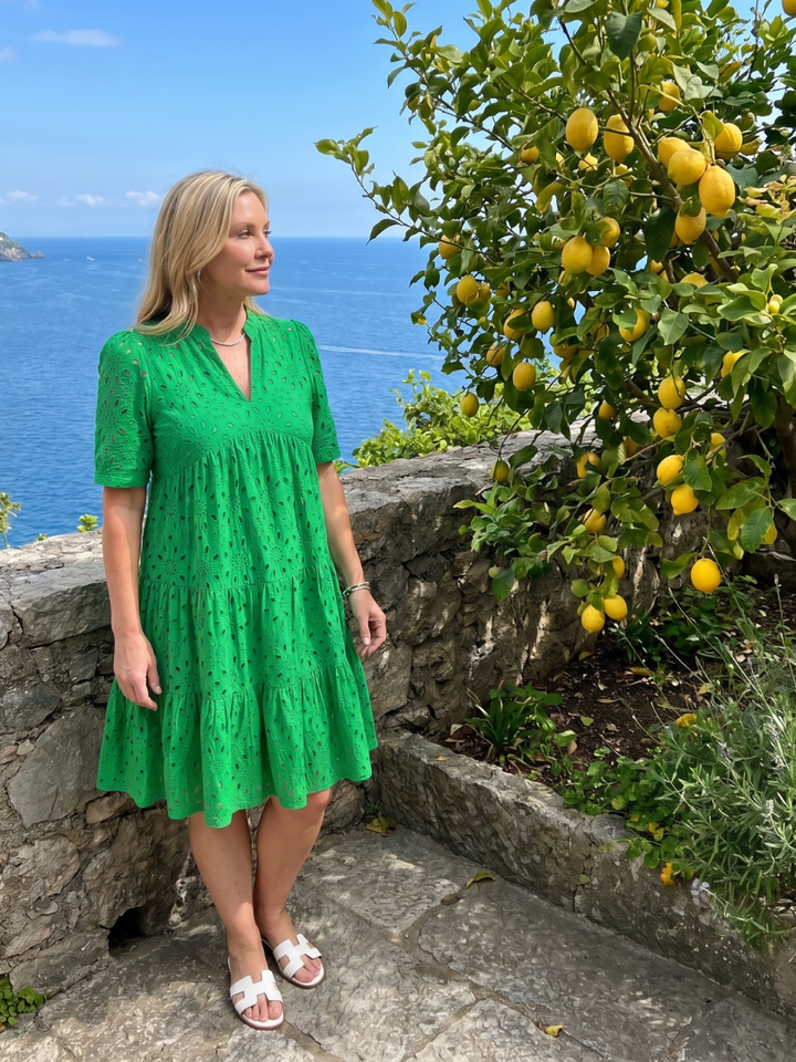 Stylish knee-length women's eyelet dress with short sleeves, V-neck, and tiered skirt for a chic summer casual look.