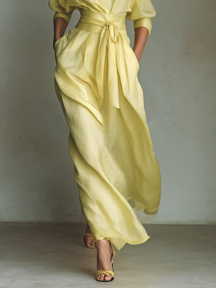 Flowy yellow maxi dress for women with a tie belt, V-neckline, and comfortable three-quarter sleeves. Casual elegant.
