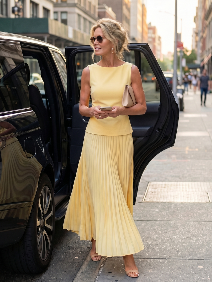 Modern women's structured sleeveless top and elegant pleated long skirt ensemble, perfect for any occasion.