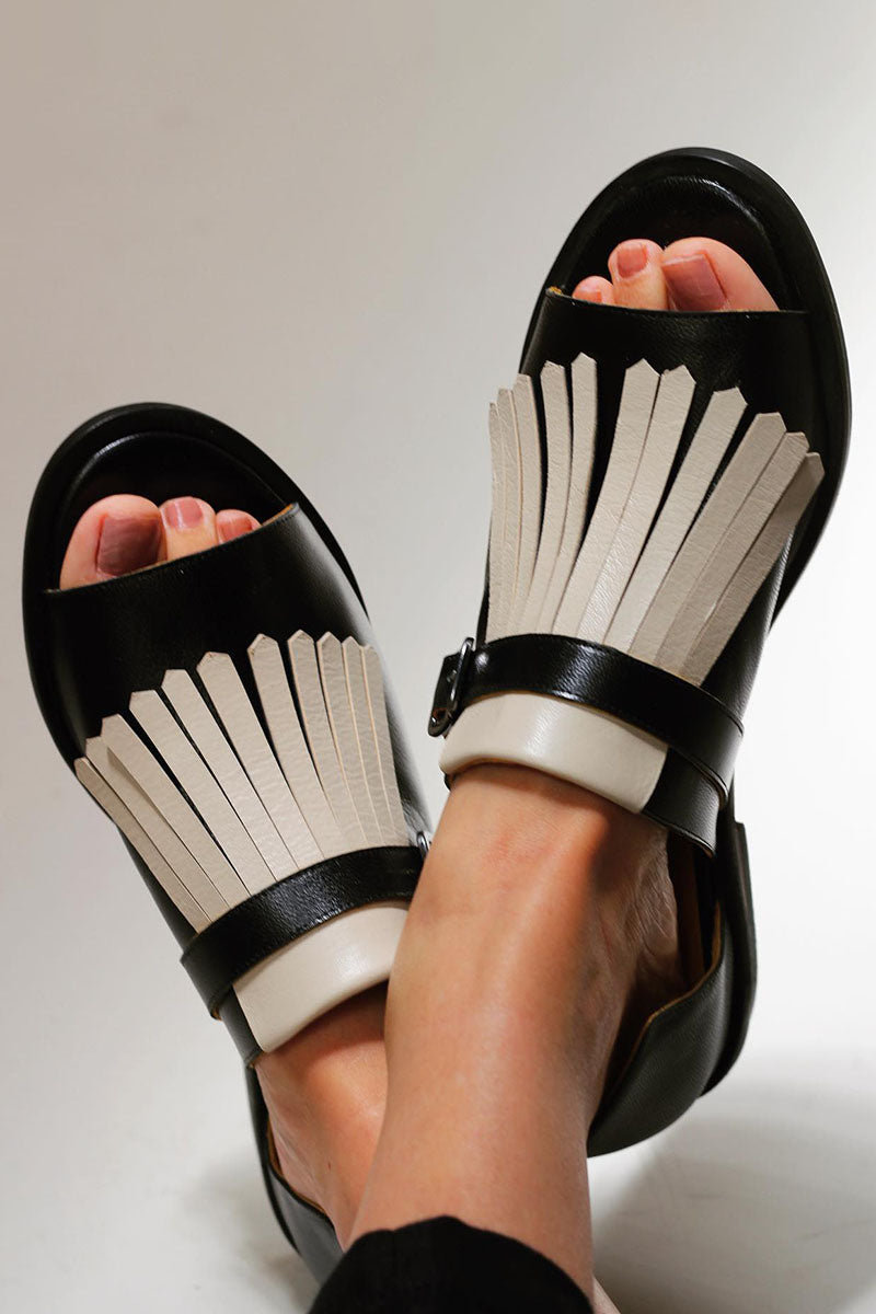 Stylish black fringe slip-on sandals for women. Fashionable open-toe summer shoes, great for warm weather casual wear.