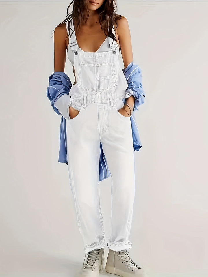 Stylish women's denim dungarees, loose fit overalls for casual wear, side view on model.