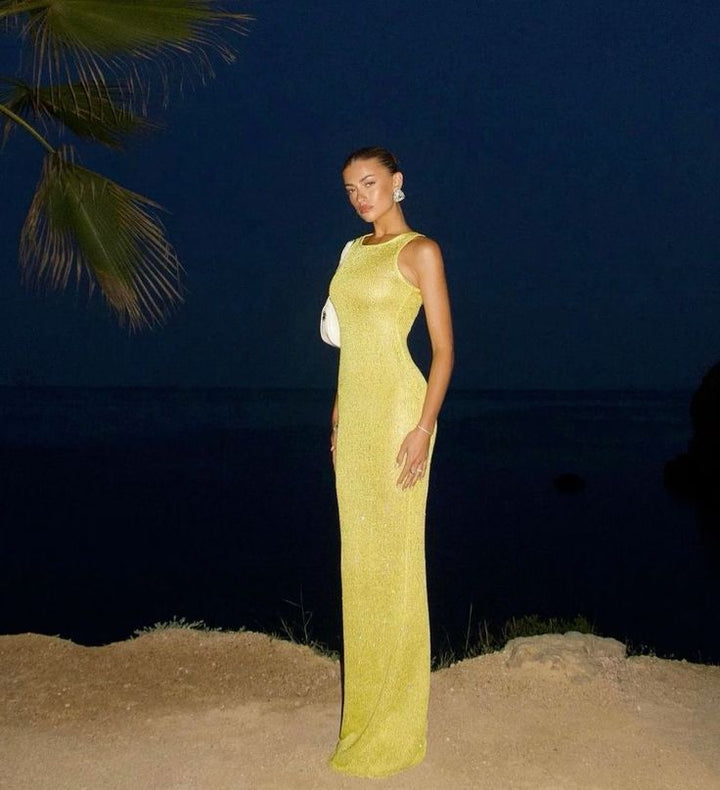 Side profile of a women's elegant shimmering yellow maxi dress, showcasing its flattering evening gown silhouette.