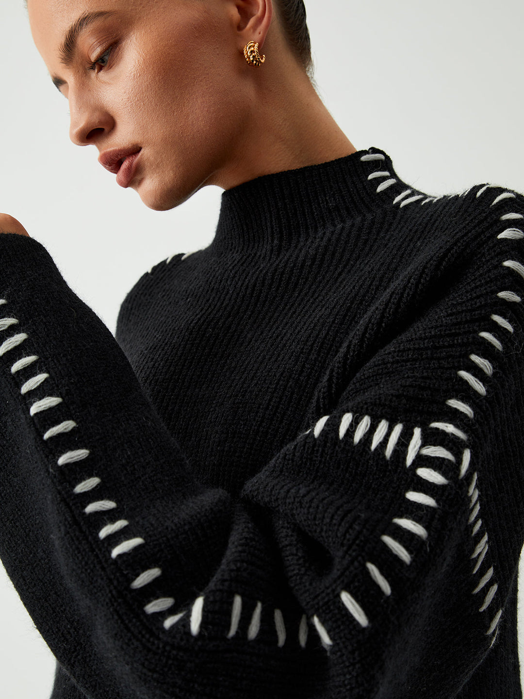 Cozy women's oversized sweater with mock neck and distinctive contrast stitch details for everyday comfort.