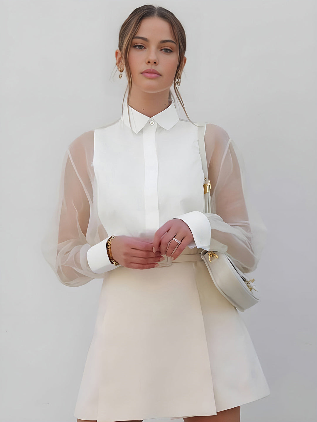 Women's white tailored set featuring a sheer sleeve button-up shirt and structured mini skirt for a chic summer outfit.