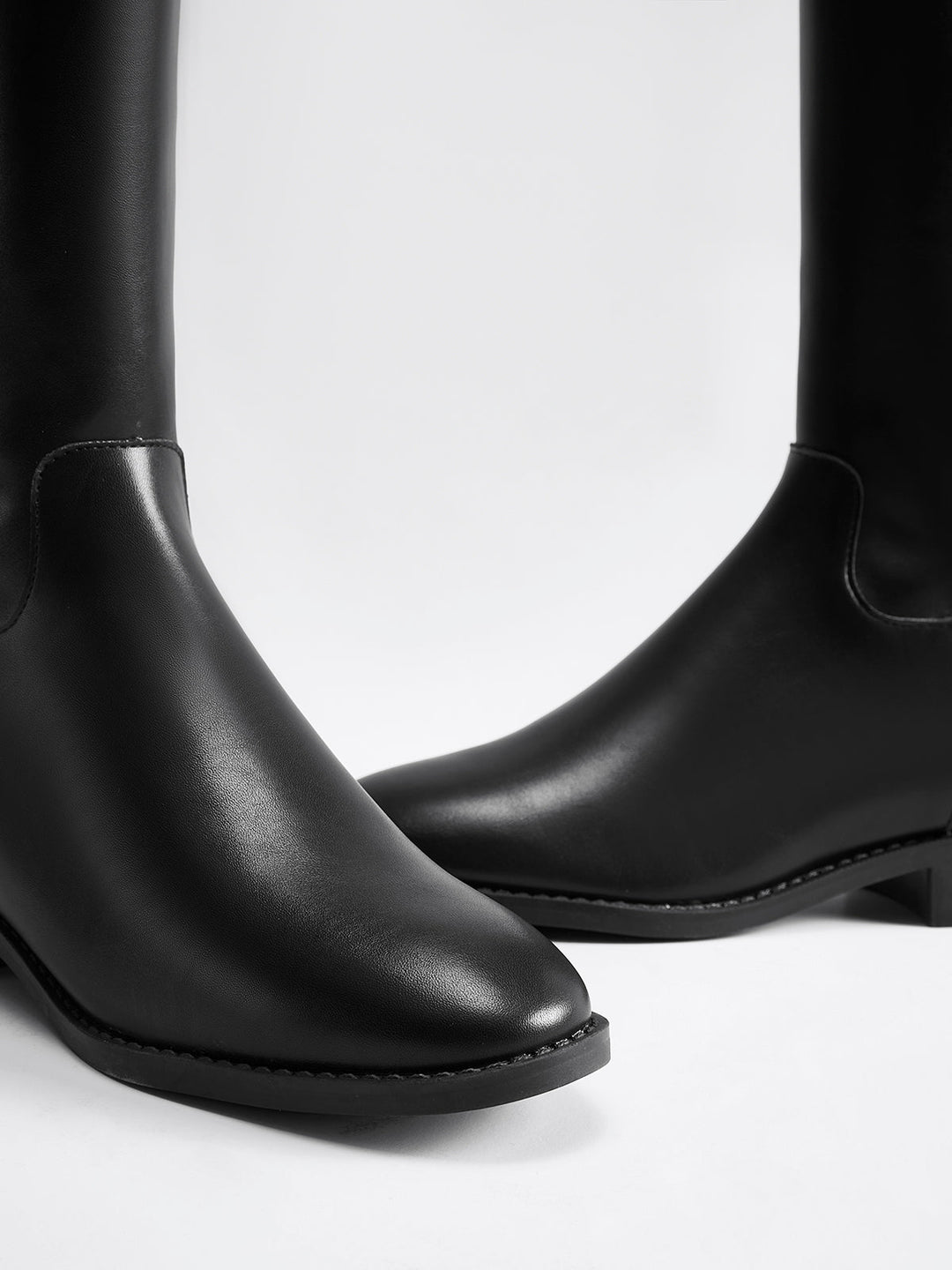 Women's sleek black knee-high riding boots, elegant & tall, a staple for classic fall & winter style.
