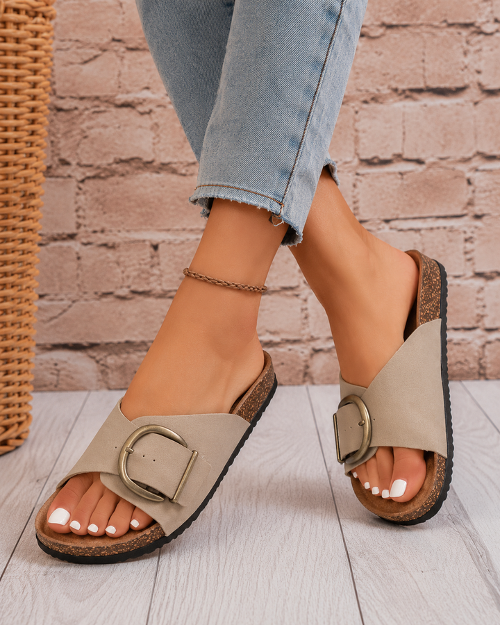 Close-up of a women's comfort slide sandal featuring a large, stylish buckle and soft footbed.
