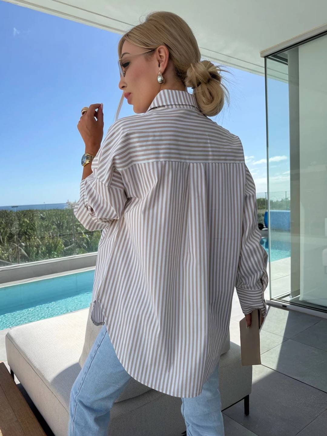 Front view of a women's elegant striped button-up blouse, showcasing its relaxed fit & detailed buttons.