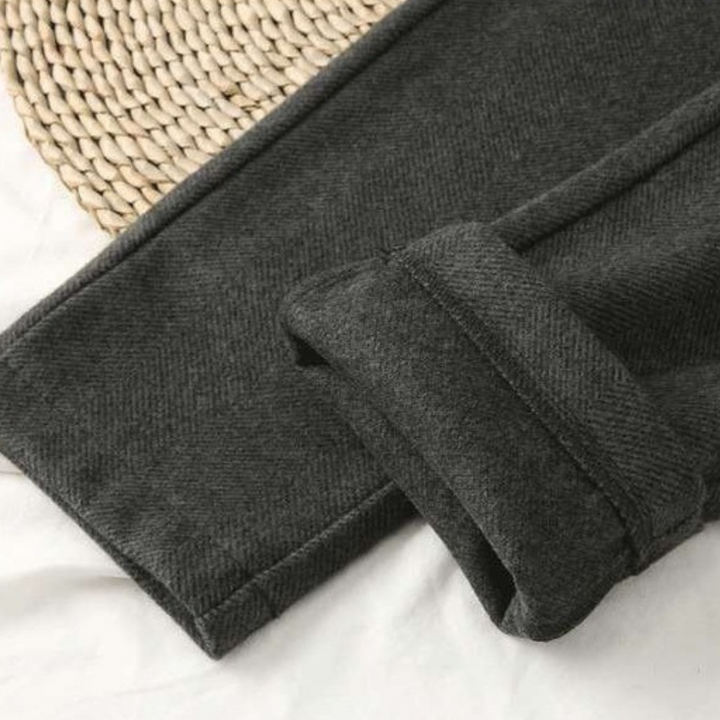 Textured close-up of luxurious herringbone pattern on women's versatile all-season trousers. Elegant & classic.