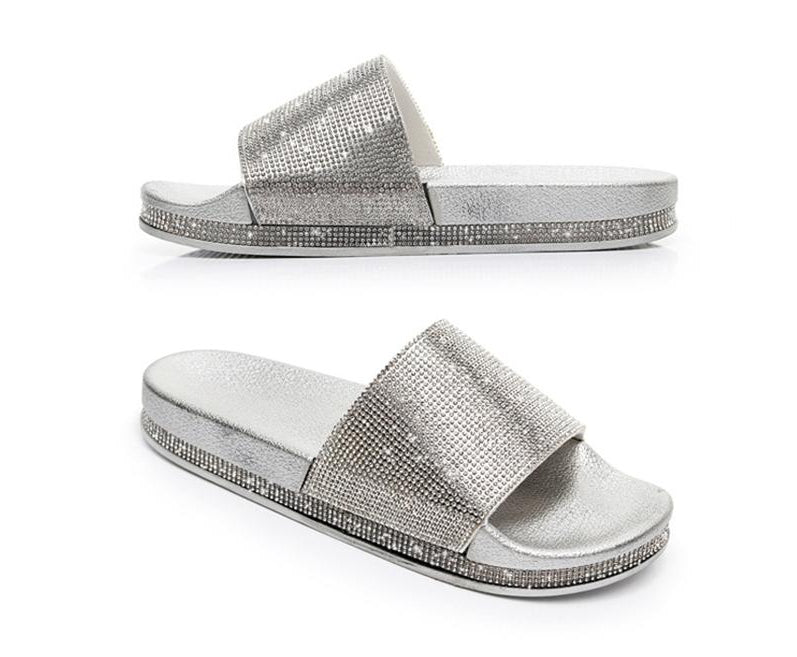 Close-up of sparkling crystal embellishments on women's slides sandals.