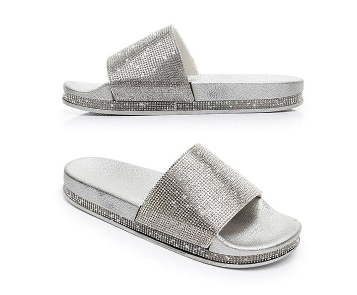Close-up of sparkling crystal embellishments on women's slides sandals.