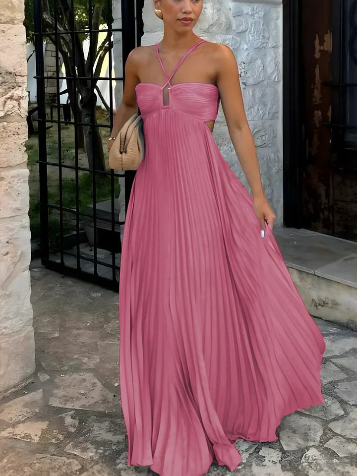 Woman in a flowing pleated halter neck maxi dress with a chic high-waisted side cut-out, ideal for parties.
