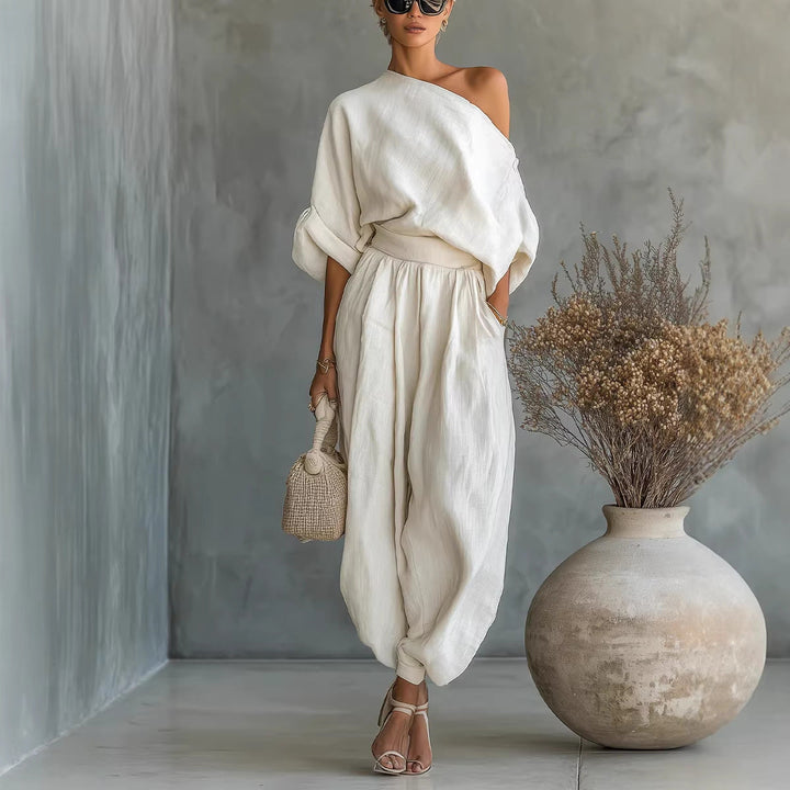 Woman wearing a cream asymmetrical neckline loose fit jumpsuit, ideal for comfortable and stylish summer fashion.