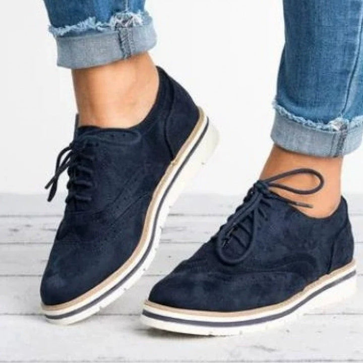 Close-up of elegant women's brogue shoes showcasing the intricate perforated design & classic lace-up detailing.