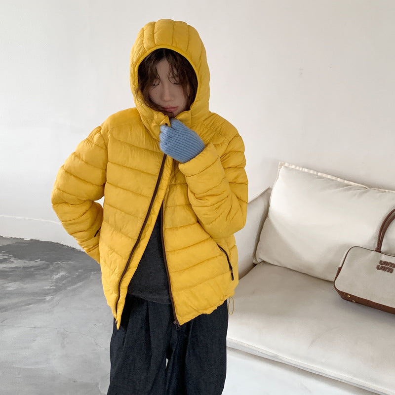 Modern women's packable puffer jacket, ultralight design & removable hood for adaptable warmth.