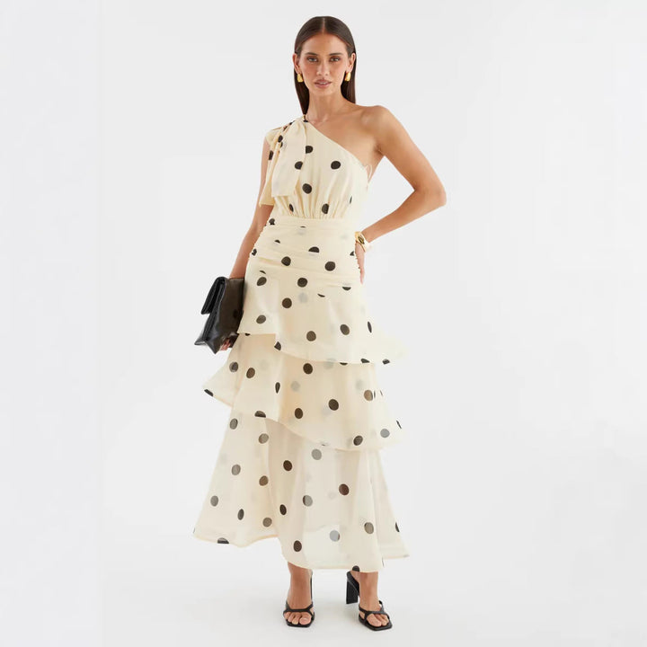 Chic polka dot evening maxi dress for women, featuring an asymmetrical neckline and a graceful voluminous skirt.