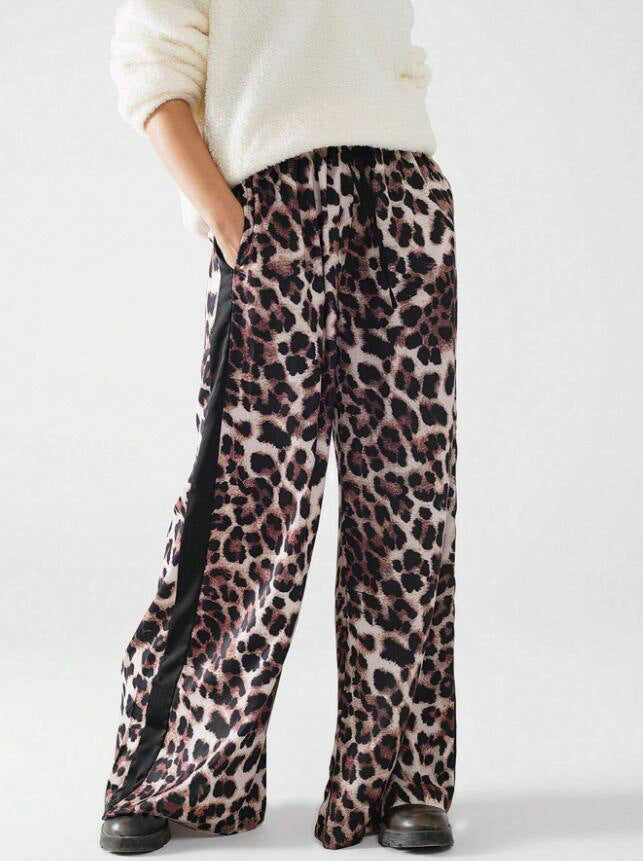 Bold leopard print wide-leg pants for women, featuring a chic loose fit & contrasting side stripe detail. Trendy bottoms.