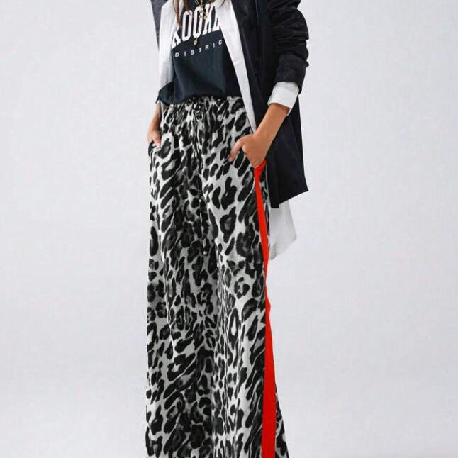 Close-up of trendy women's leopard print wide-leg pants, highlighting the chic pattern & contrasting side stripe detail.