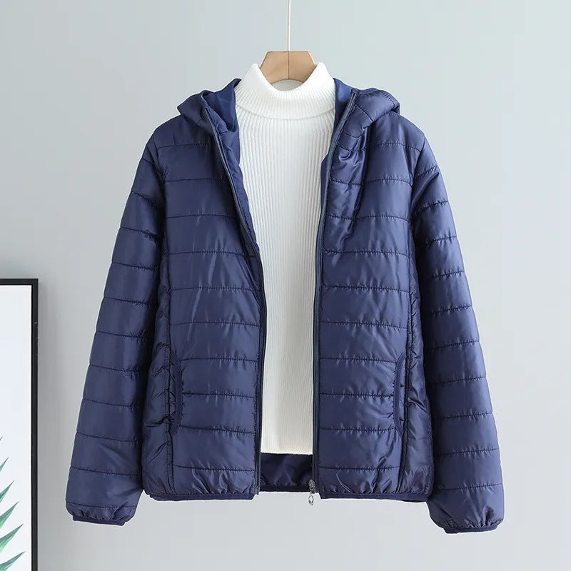 Side view of a women's lightweight quilted jacket with hood, showing elastic cuffs & hem.