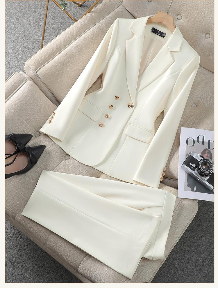 Crisp white women's two-piece blazer and pants set, featuring elegant golden buttons for a chic professional look.