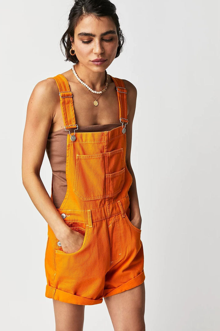 Woman wearing casual denim overall shorts, perfect for a relaxed summer day, with pockets & adjustable straps.