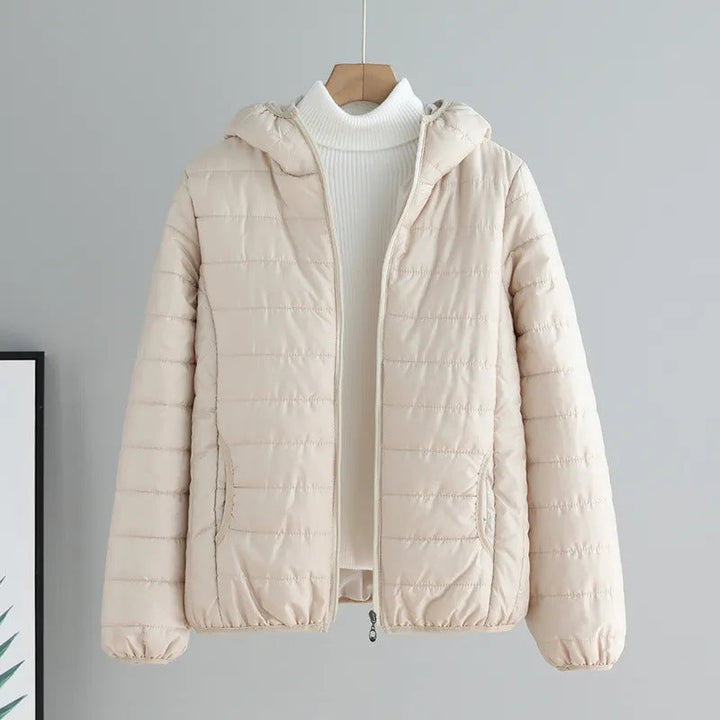 Stylish women's pink quilted transitional jacket with hood, functional front pockets.