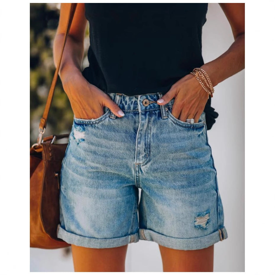 Casual women's light blue denim shorts featuring trendy distressed details & a comfortable rolled hem.