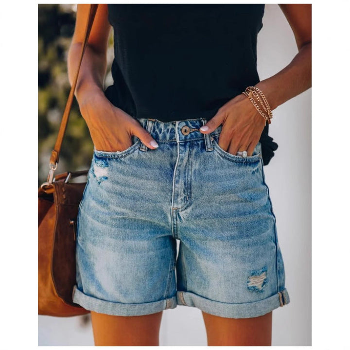 Casual women's light blue denim shorts featuring trendy distressed details & a comfortable rolled hem.