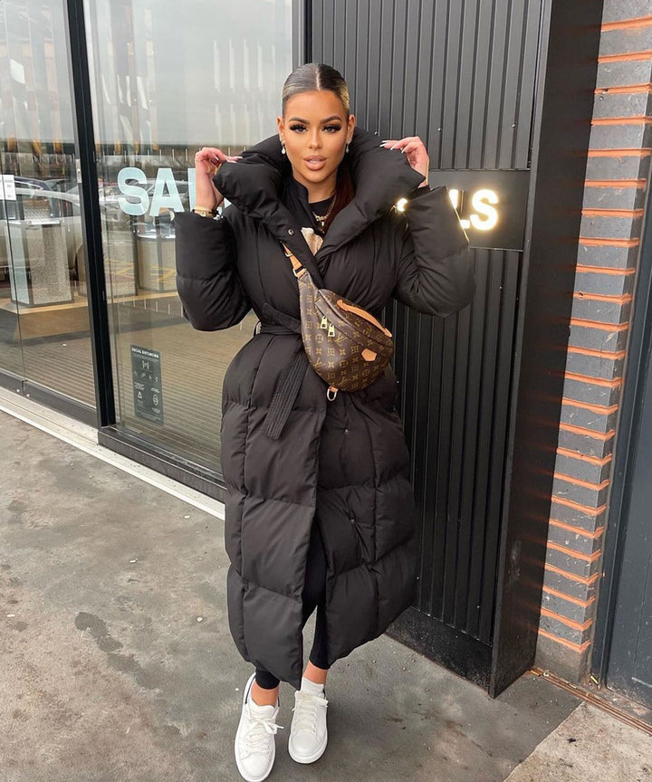 Women's sophisticated long quilted winter coat with high collar, belted for an elegant silhouette.