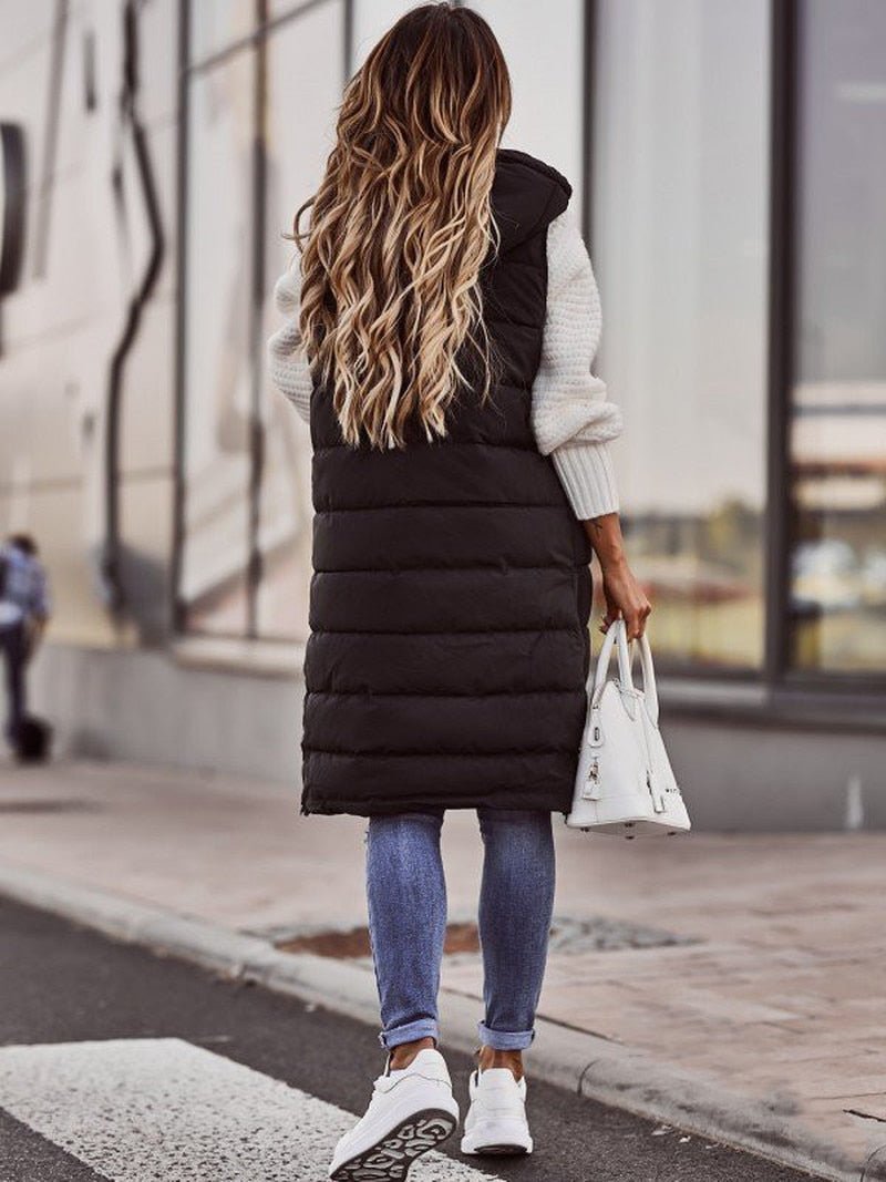 Modern women's long hooded puffer vest with a sleek quilted design. Versatile sleeveless jacket for fall/winter layering.