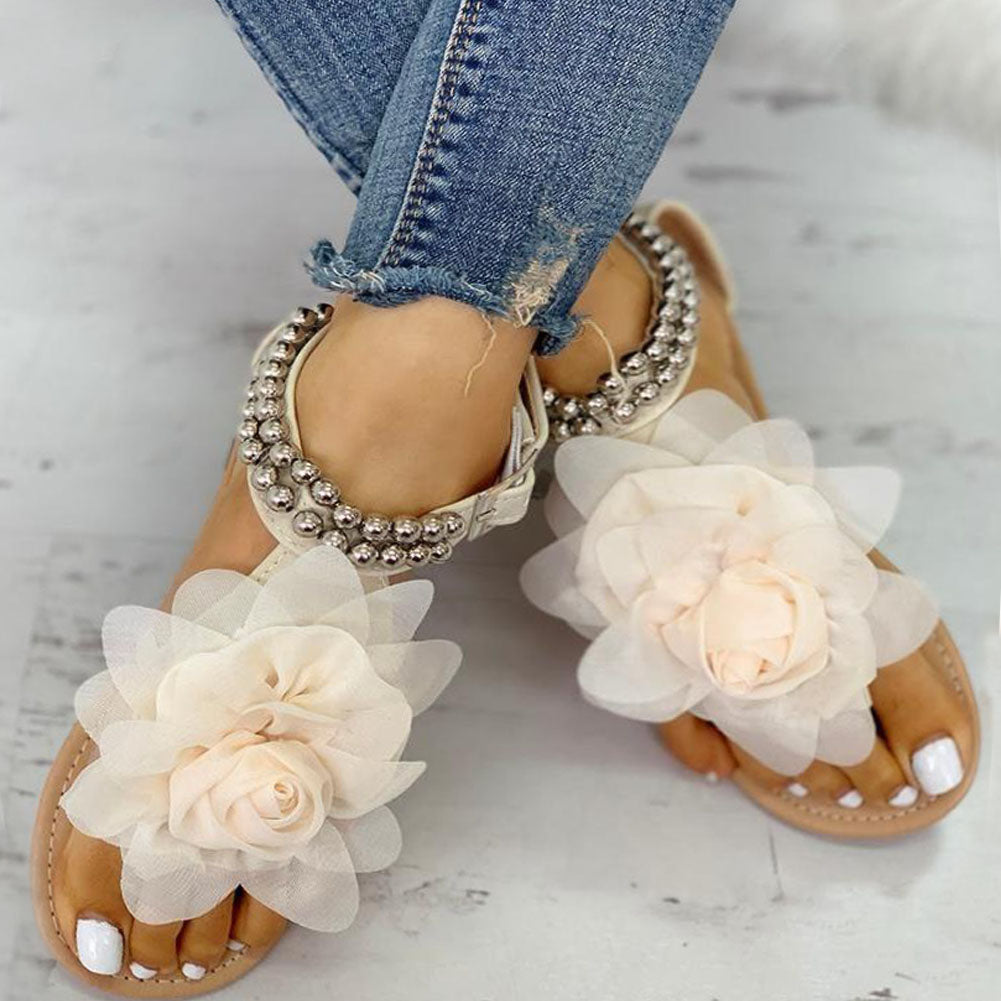 Chic women's flat sandals with elegant flower and pearl beaded ankle straps, offering comfortable summer fashion.