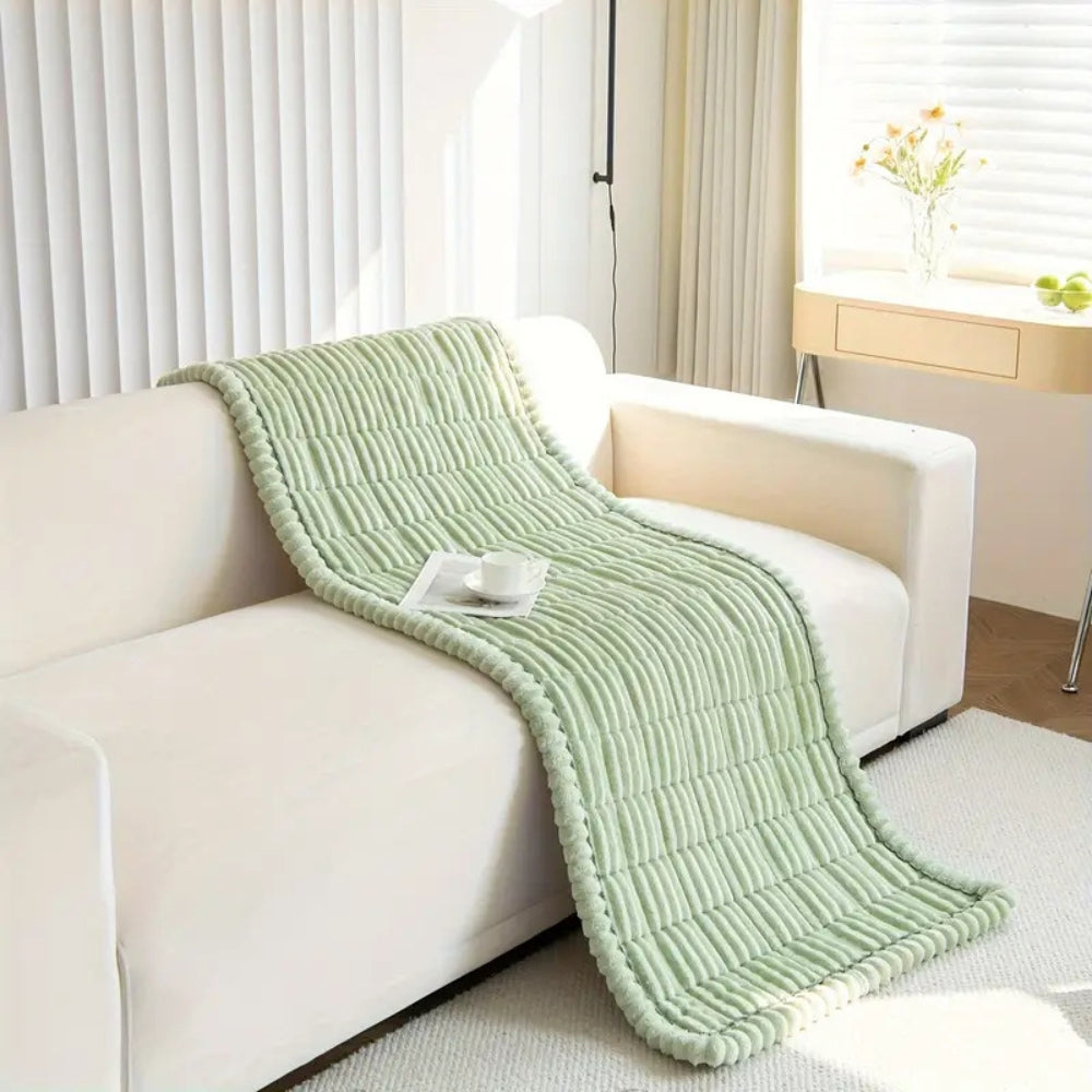 Plush fleece sofa protector mat on a living room couch. Non-slip quilted cover providing comfort and furniture safety.