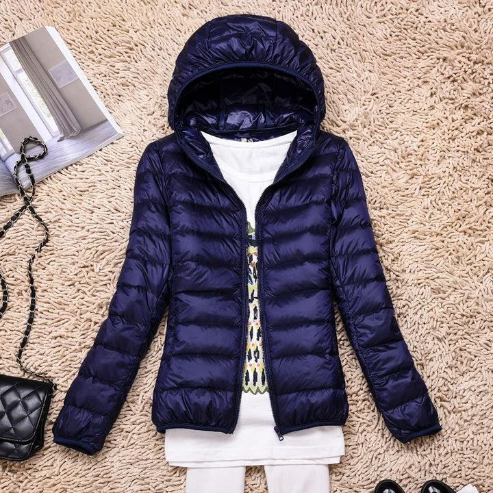 Hooded women's packable insulated jacket. Lightweight winter outerwear, weather-resistant for travel.