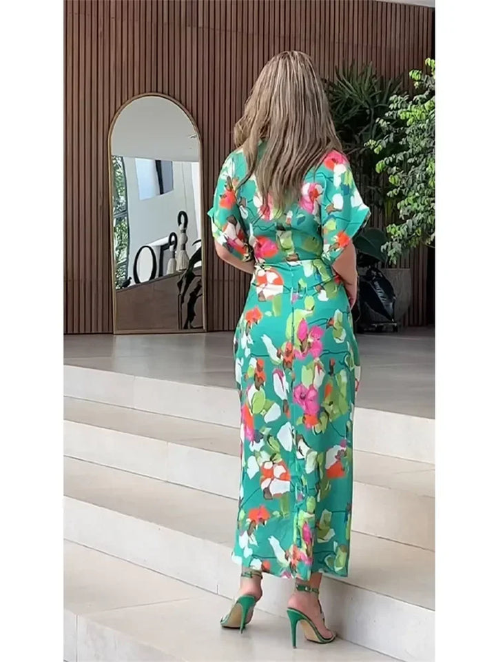 Close-up of the flowing fabric and green floral pattern on this women's elegant button-down maxi dress.