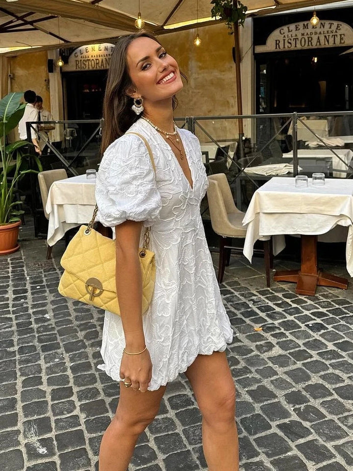 Woman enjoying summer in a romantic white floral mini dress with puff sleeves, perfect for day outings.