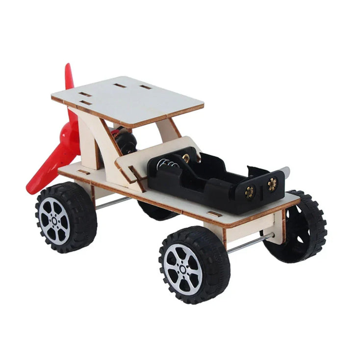 Close-up of wooden electric toy boat kit parts: wood, motor, battery case, and propeller.