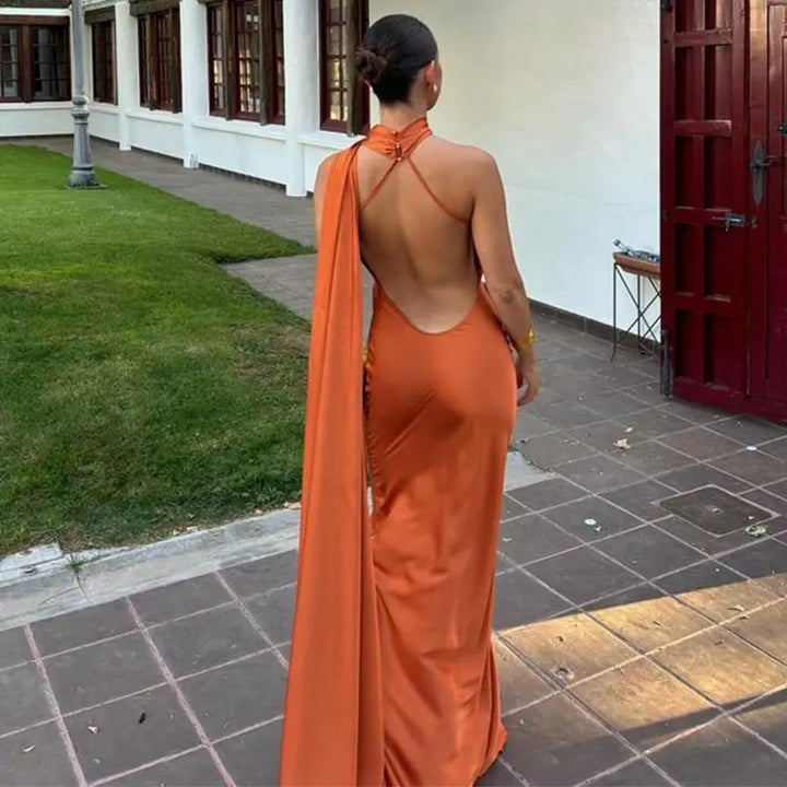 Graceful women's one-shoulder cape maxi dress flowing elegantly. Formal evening gown perfect for a special occasion.